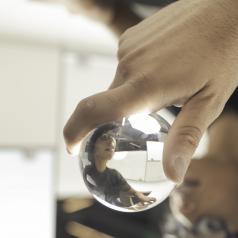 Person holds glass ball, in which they are reflected