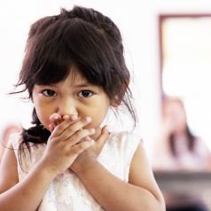 Girl covering her mouth with her hands, looking anxious