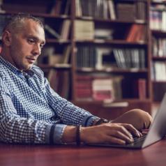 Adult with short hair does research on computer in library