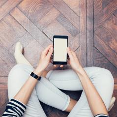 Overhead view of person sitting on wood floor holding a smartphone
