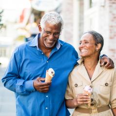 Older couple walks together eating ice cream, talking and laughing