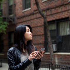 Girl in leather jacket explores city, using her phone for directions