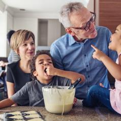 Two grandparents teach kids how to make cupcakes (while one kid taste tests the batter!).