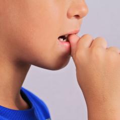 Close-up of a child biting their nail.