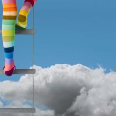 Legs in rainbow stockings climbing a ladder into the sky