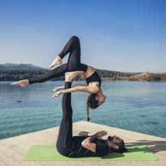 Couple practicing acroyoga in nature at beautiful lake