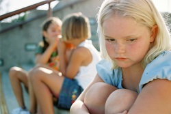 Young girl appears distressed as peers whisper in the background